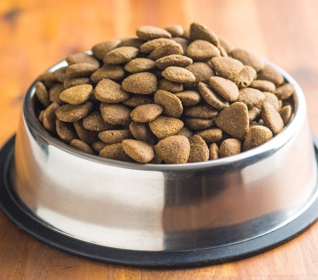 dog food in a metal bowl on a wooden table